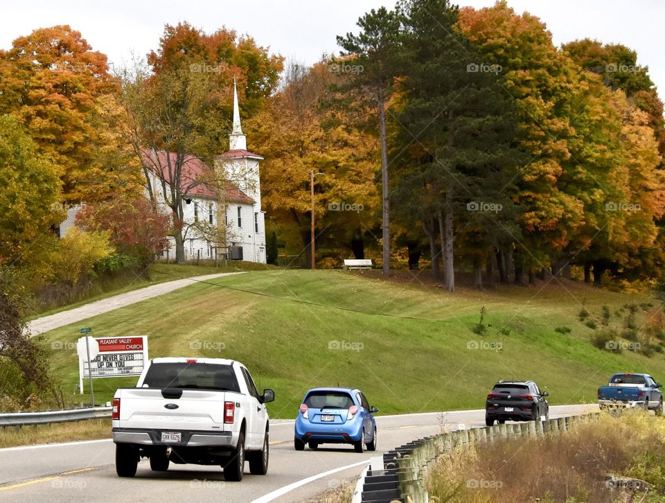 Cars on a country road going by an old church