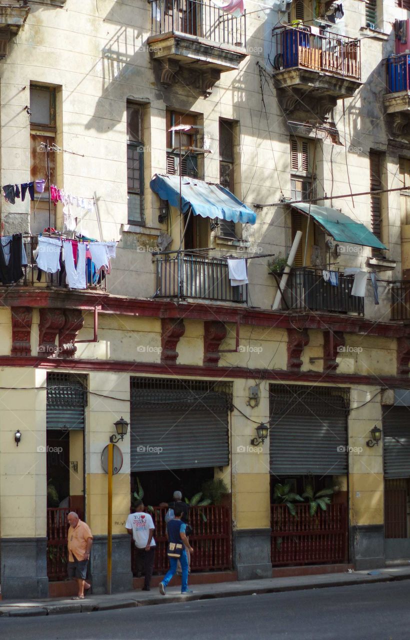 People walking along a street in Havana.  Beautiful houses with typical balconies