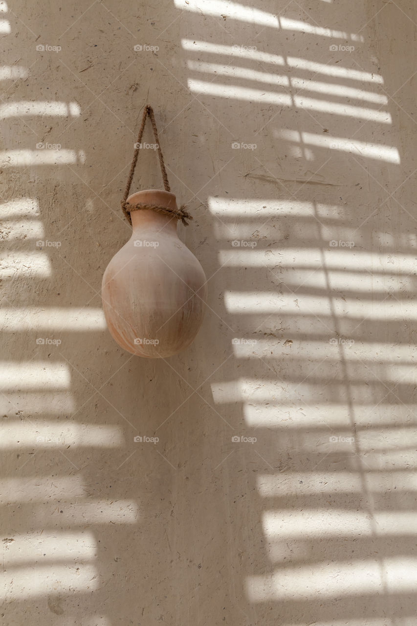 Clay pot hanging on a shadowed wall