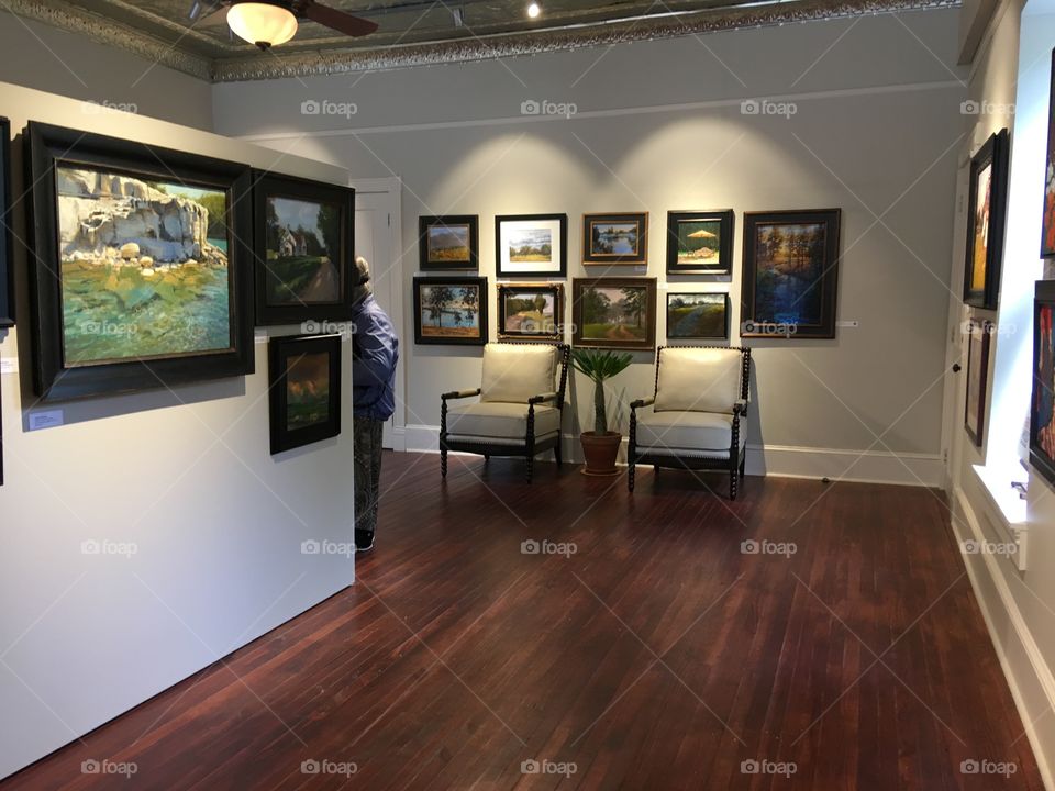 Lightning hi lightning two chairs sitting underneath a group of paintings more on the left.