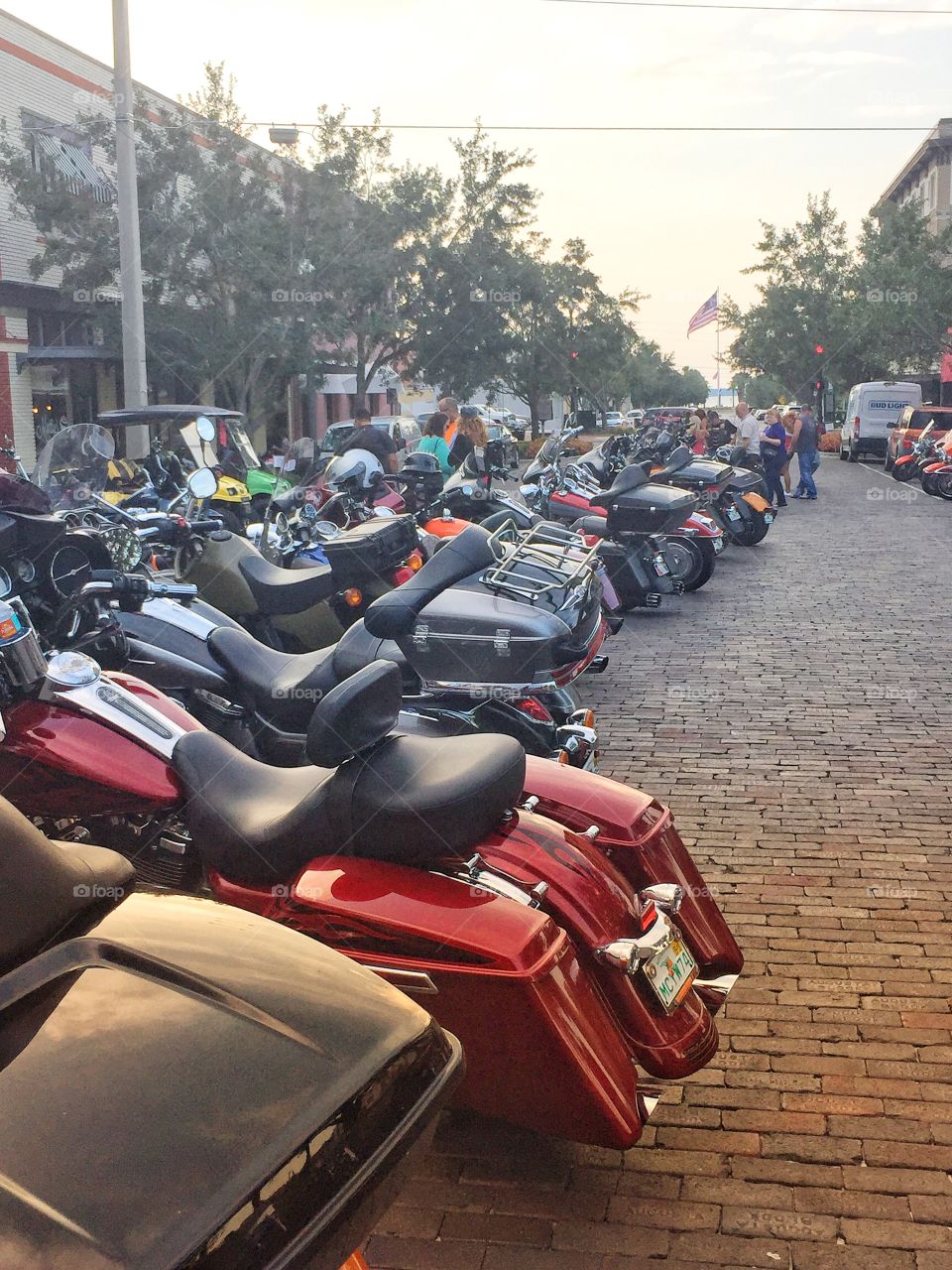 Motorcycles lined up down a brick covered street
