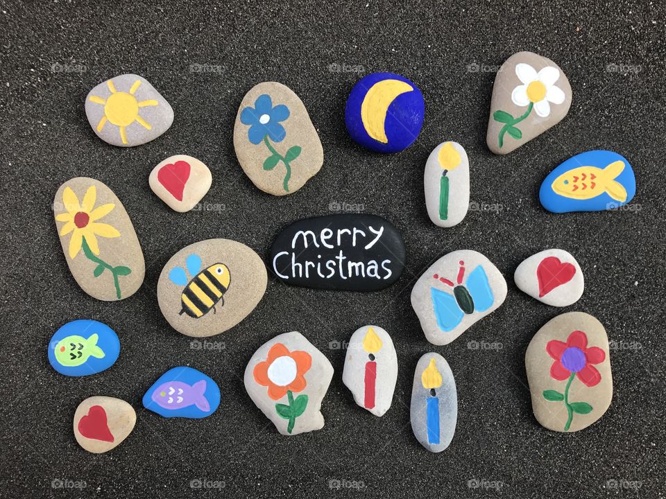 Merry Christmas on a black stone over volcanic sand 
