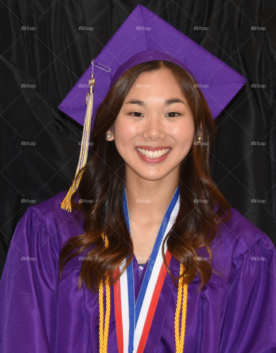 Graduating girl with purple cap and gown and honor cords