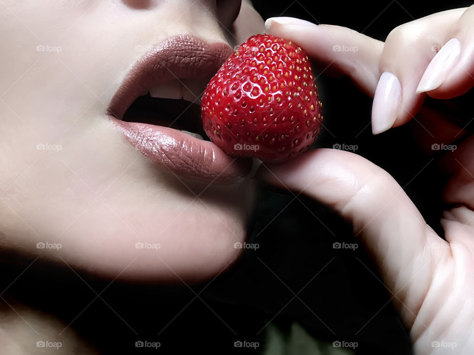 Woman eating a red strawberry 