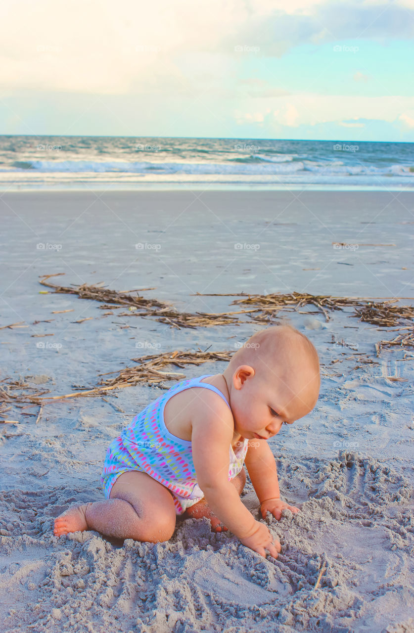 Cute baby playing at beach with sand