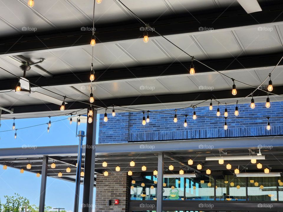 outdoor dining strings of light bulbs during the daytime