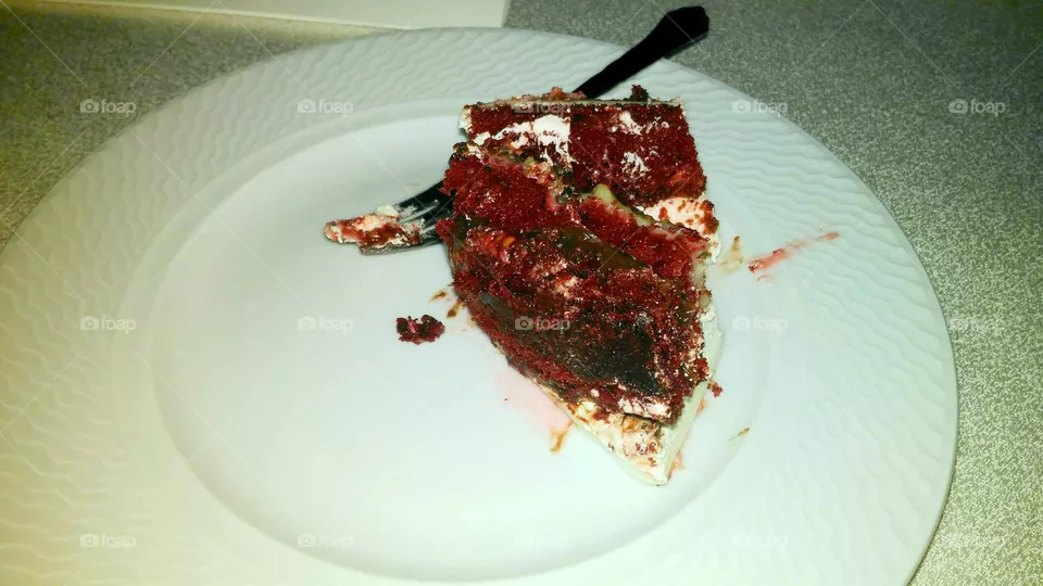 A slice of velvet wedding cake served in a dessert plate and a fork