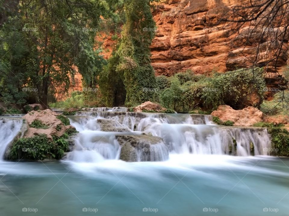 A bright blue cascade of falls contrasts with the orange canyon walls in Havasupai
