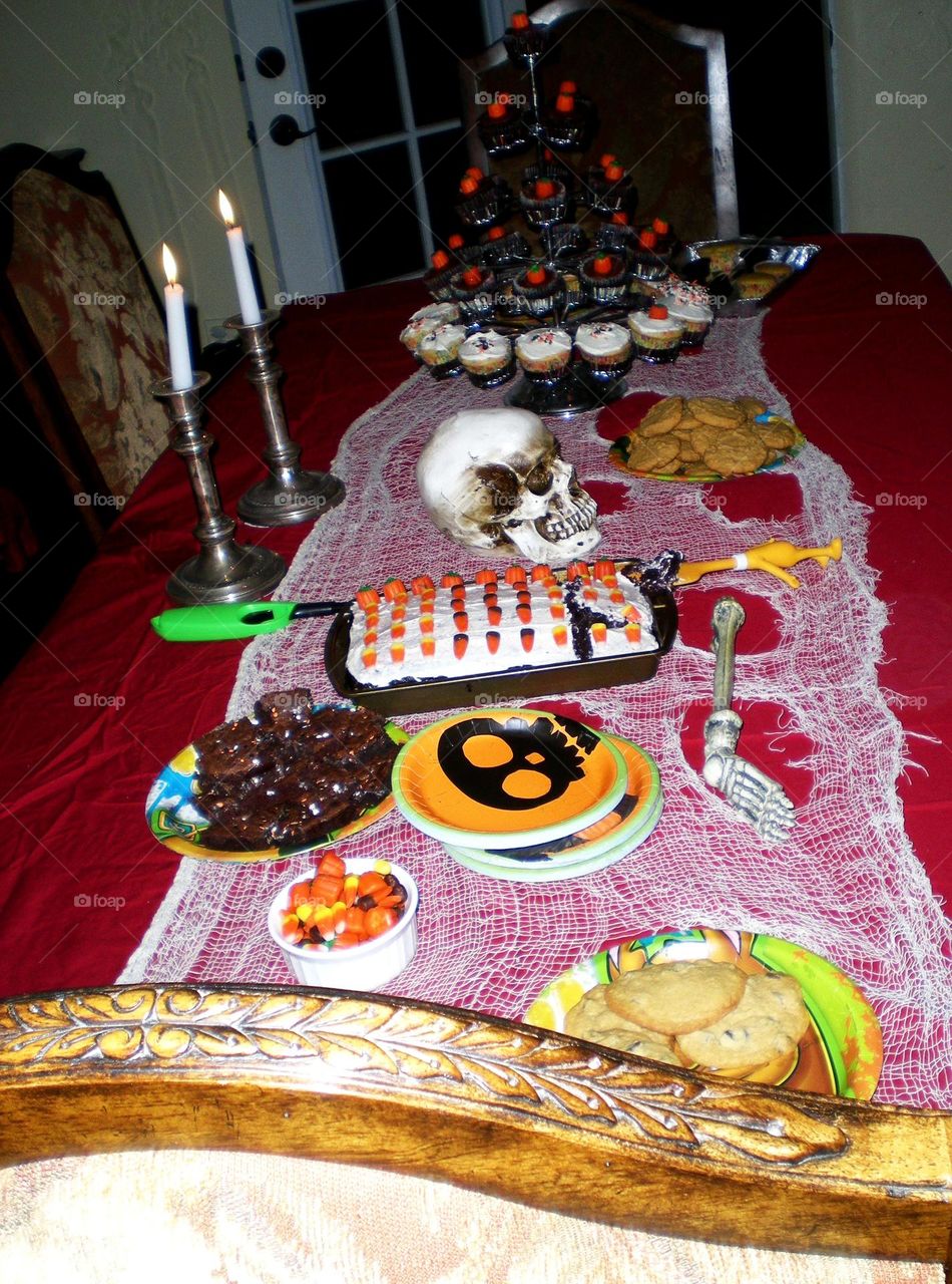 view of a spooky fun skeleton themed Halloween Party dessert table at night in a CA home