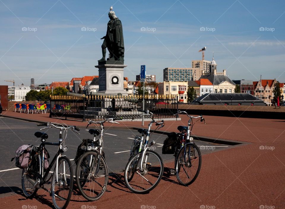 Bicycles and a statue with a bird on top in the city square 