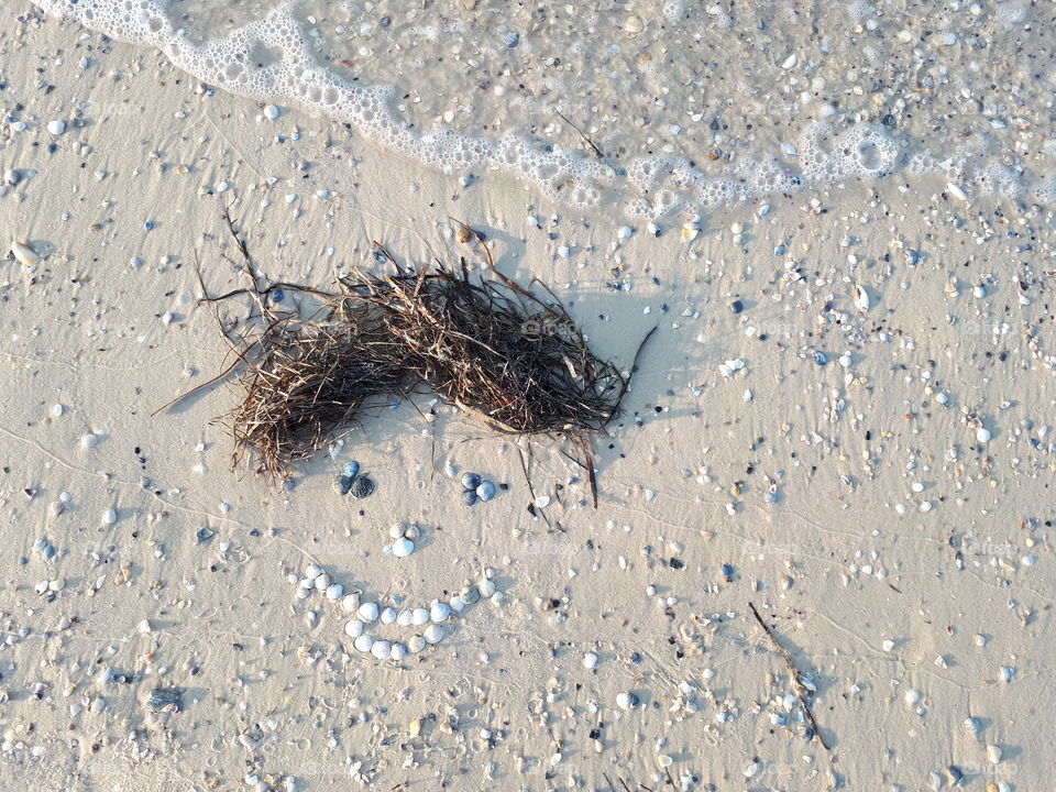 Smiling face on the sand from shells