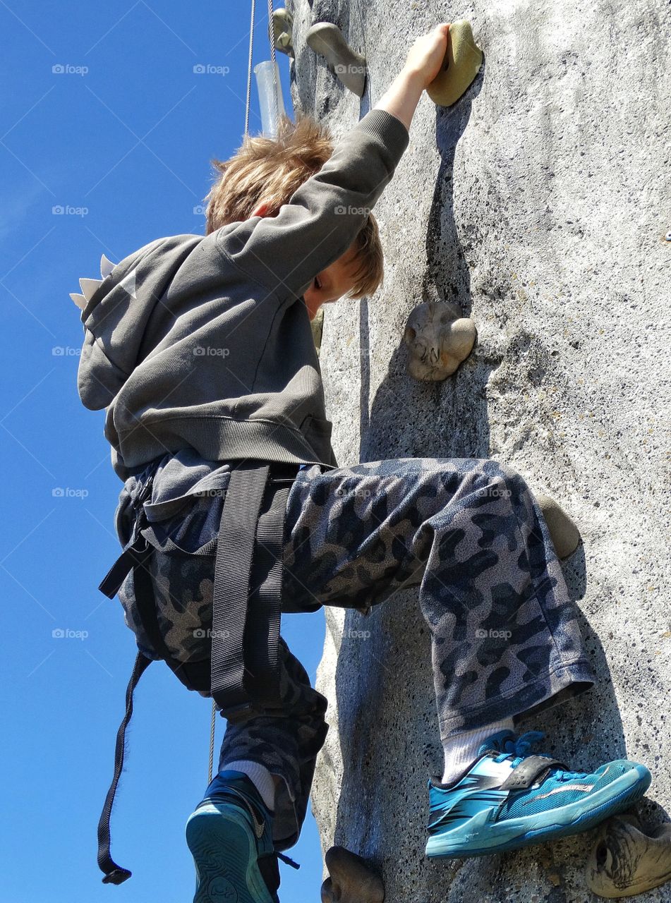 Climbing A Rock Wall. Young Boy Climbing A Rock Wall
