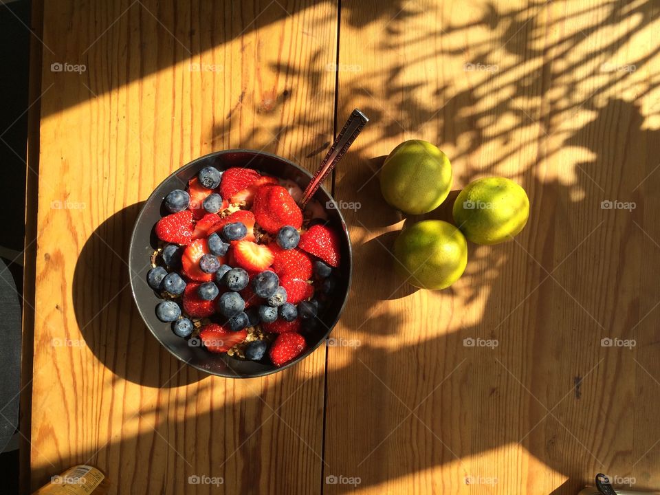 breakfast bowl with blueberries and strawberries with three lime in the side