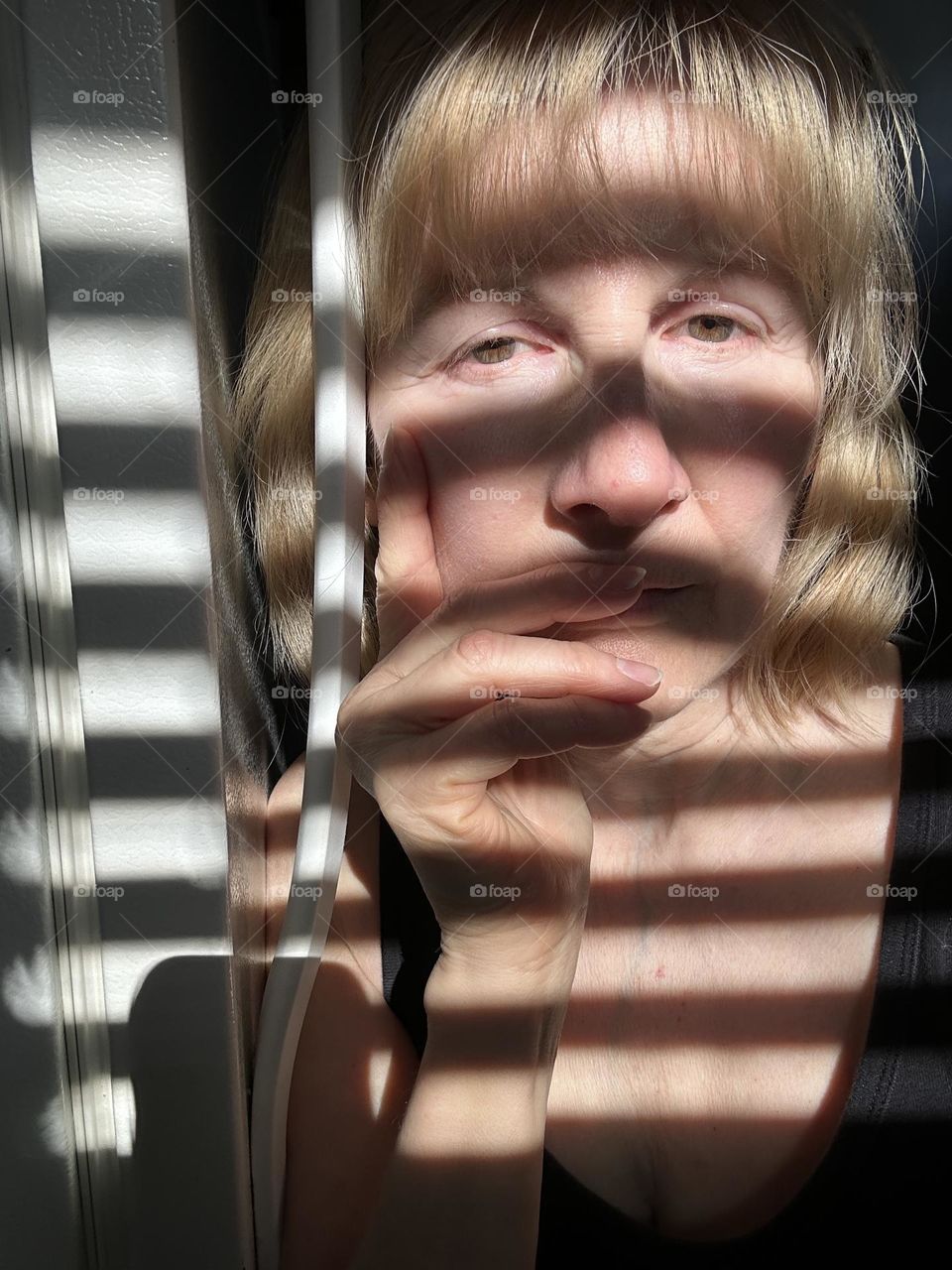 Woman with shadows from blind across her image