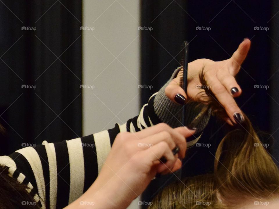 Beauty salon, hair stylist cutting young men’s hair. Person from behind, emphasis on action of hands with scissor