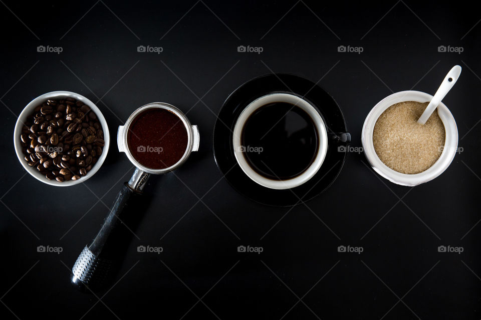 Monochrome image of a coffee making process - brown and black. Image of coffee beans to cup on a black background