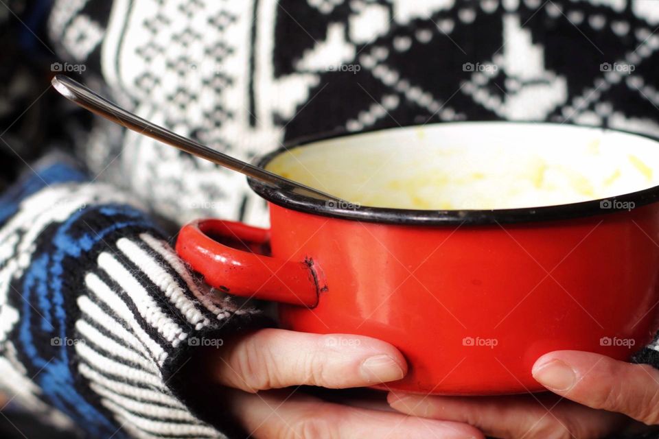 Close-up of a small red saucepan held in hands