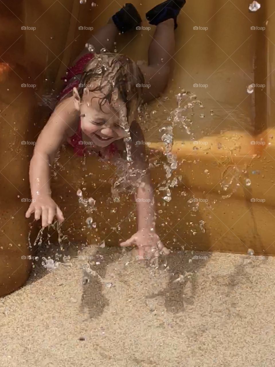 Toddler girl face first down water slide