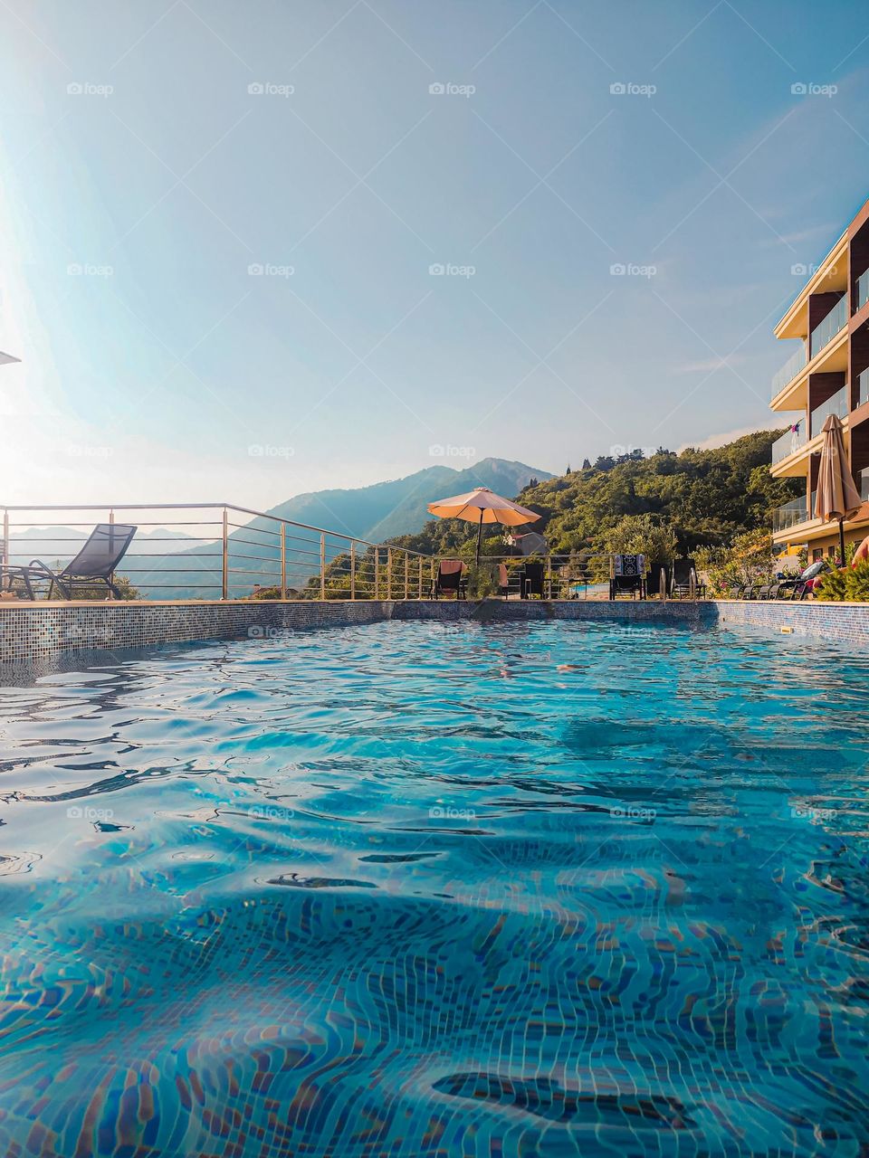 A pool in a countryside hotel, with the black mountains of Montenegro in the background. Sun is about to set down. Amazing vacation place.
