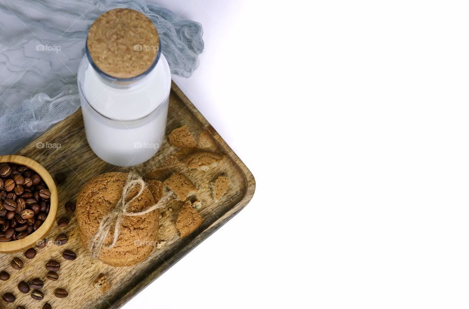 bottle with milk and oatmeal cookies on a wooden tray on a white background for the inscription