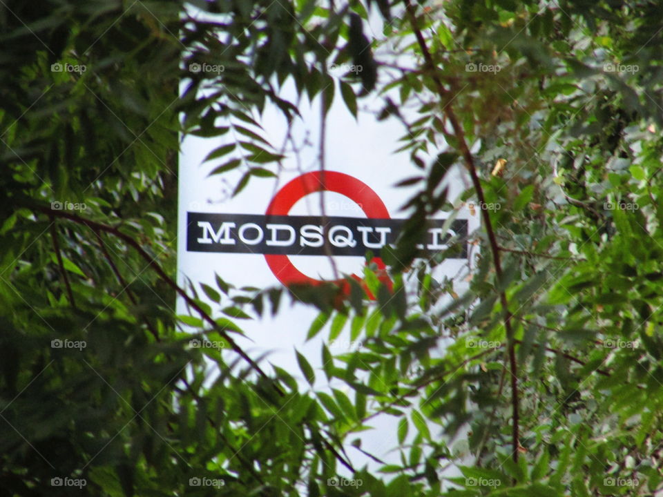 red,black and white building sign peeking through the trees