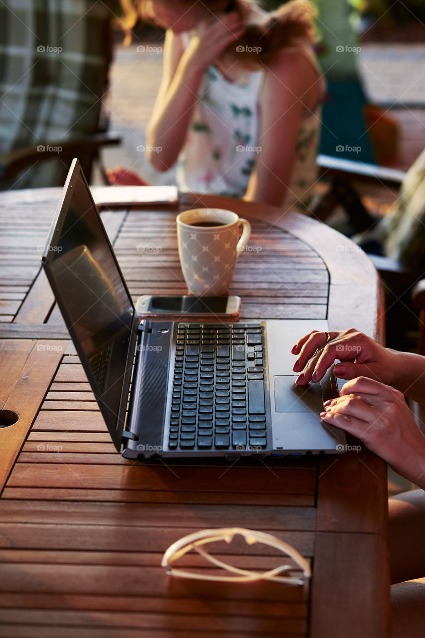 Woman working at home, using portable computer, sitting on patio on summer day. Candid people, real moments, authentic situations