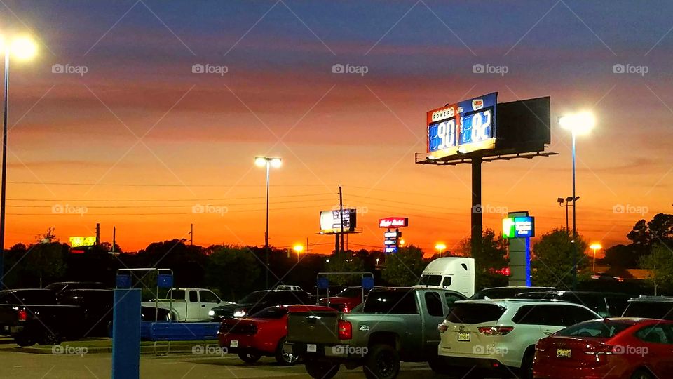 Lottery sign and other store signs and vehicles in a parking lot at sunset in Beaumont Texas USA 2017