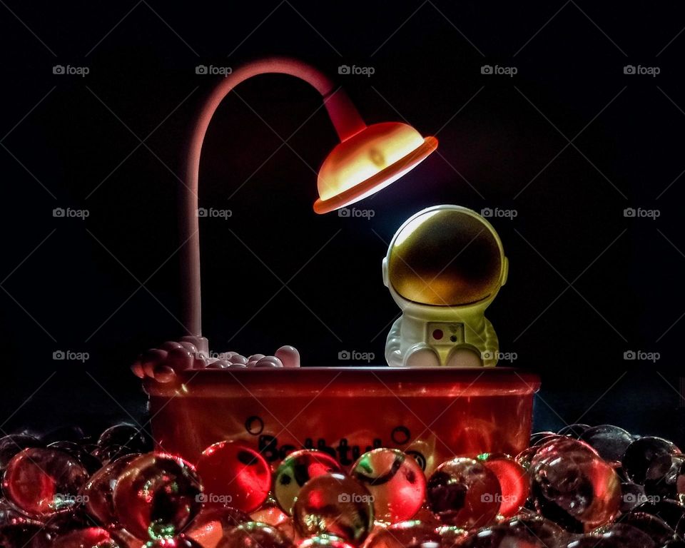 astronaut toy in a bathtub with gel balls underneath