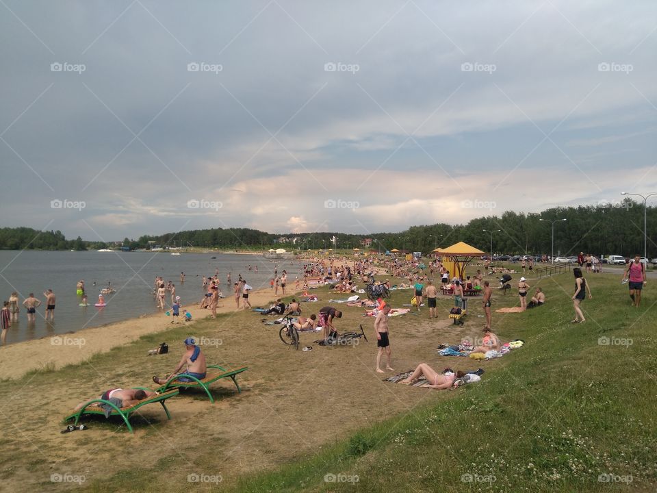 people resting on a lake shore summer time