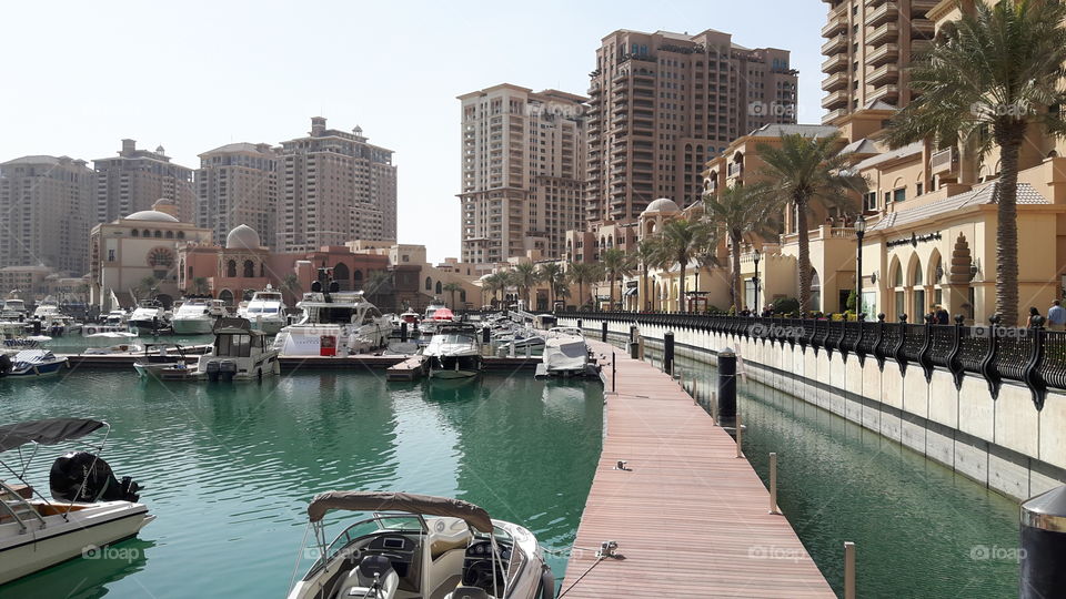 Walkway on the water/ Surrounded by luxury hotels and boats/ Beautiful sunshine day