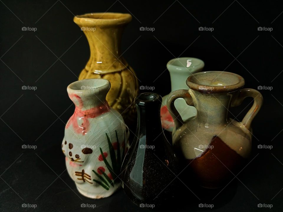 Still life with Variations of earhenware Pot and bottles isolated on black background