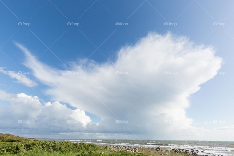Big summer clouds rising above the ocean on a sunny day with blue sky 