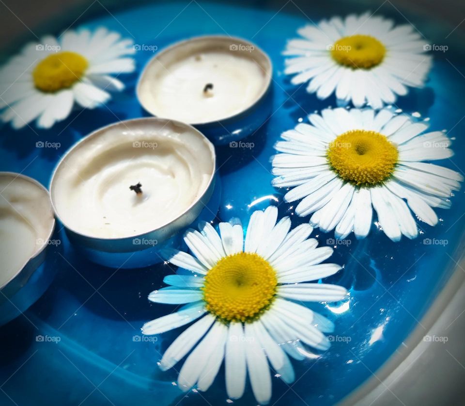 Daisy flowers and candles in blue water