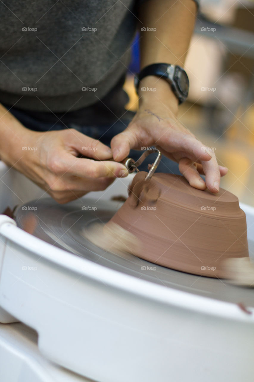 A potter works on the wheel with tools