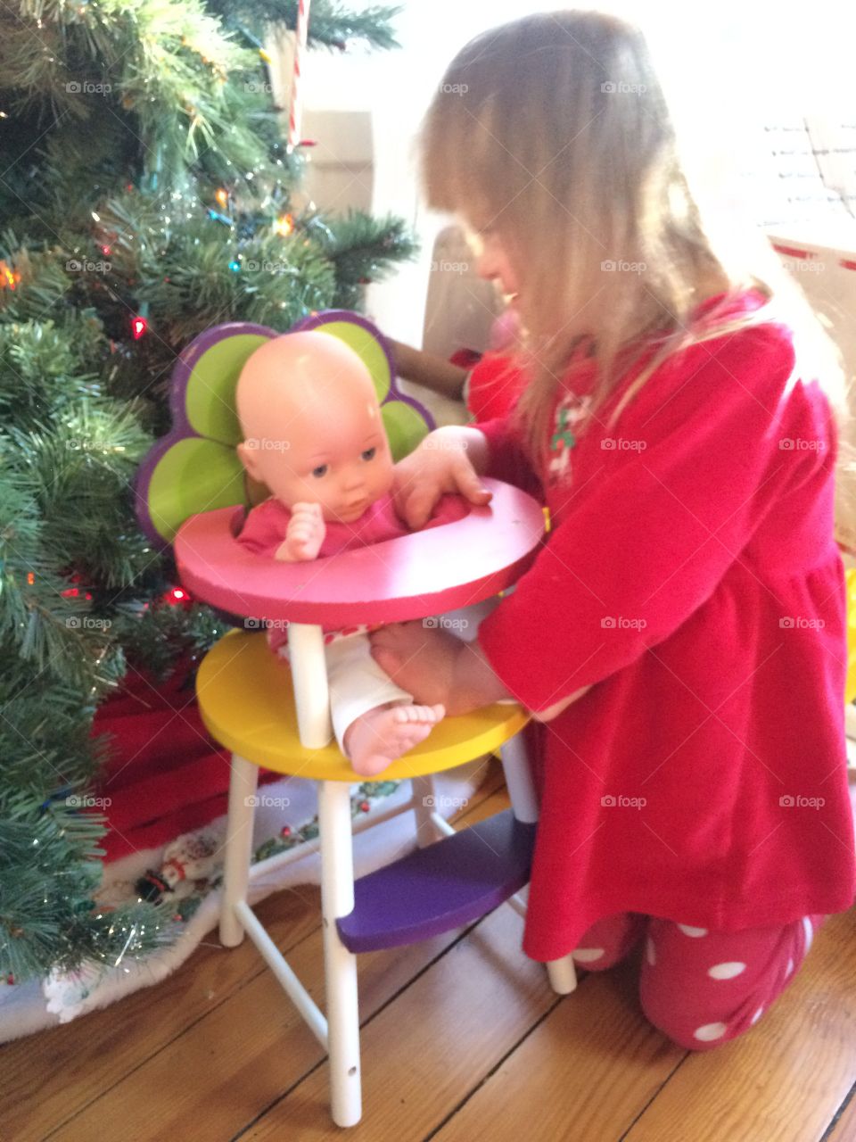 You g rl with Down syndrome playing with doll by Christmas tree