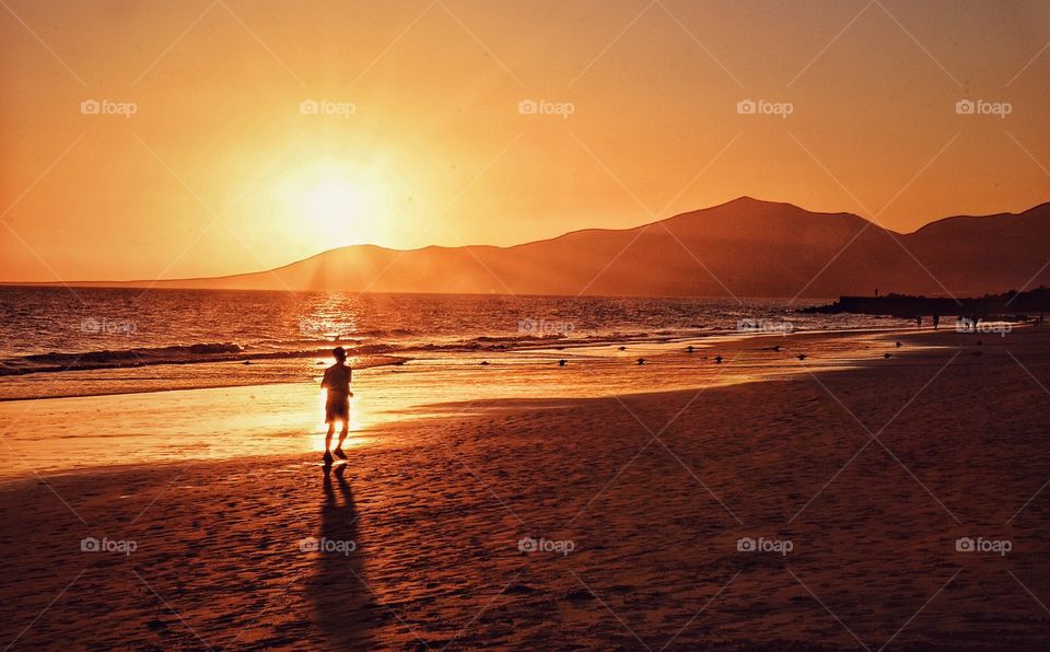Photo of a runner during sunset at the beach