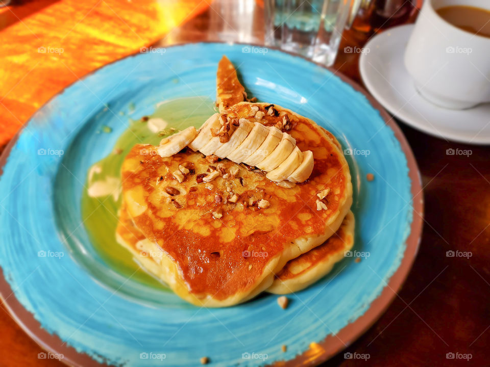 Pancakes withth banana slices, nuts and syrup.