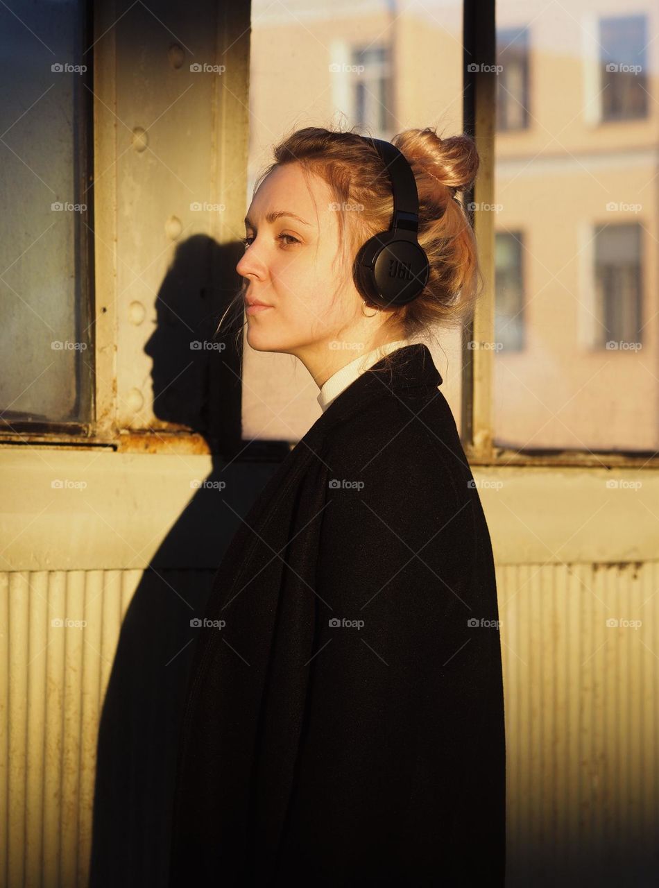 Young beautiful blonde girl in headphones in sunny day 