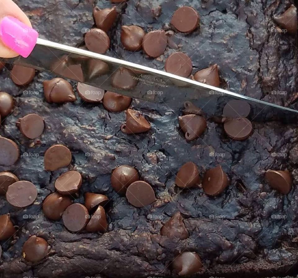 Slicing fudge chocolate chip brownies.