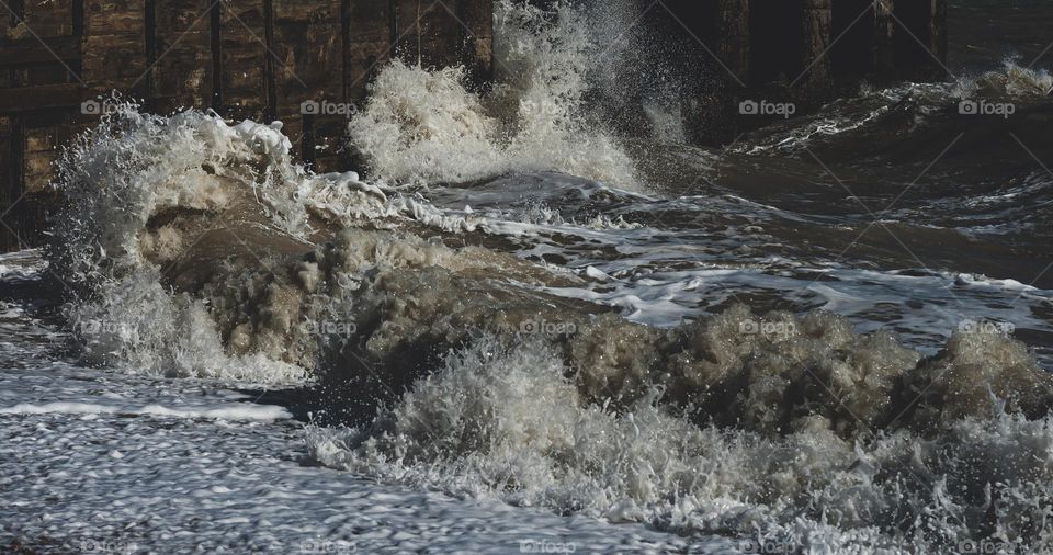 Waves crash into wooden breakers on the English coast
