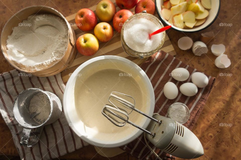 Making an apple pie dough using eggs, flour, sugar and apples.