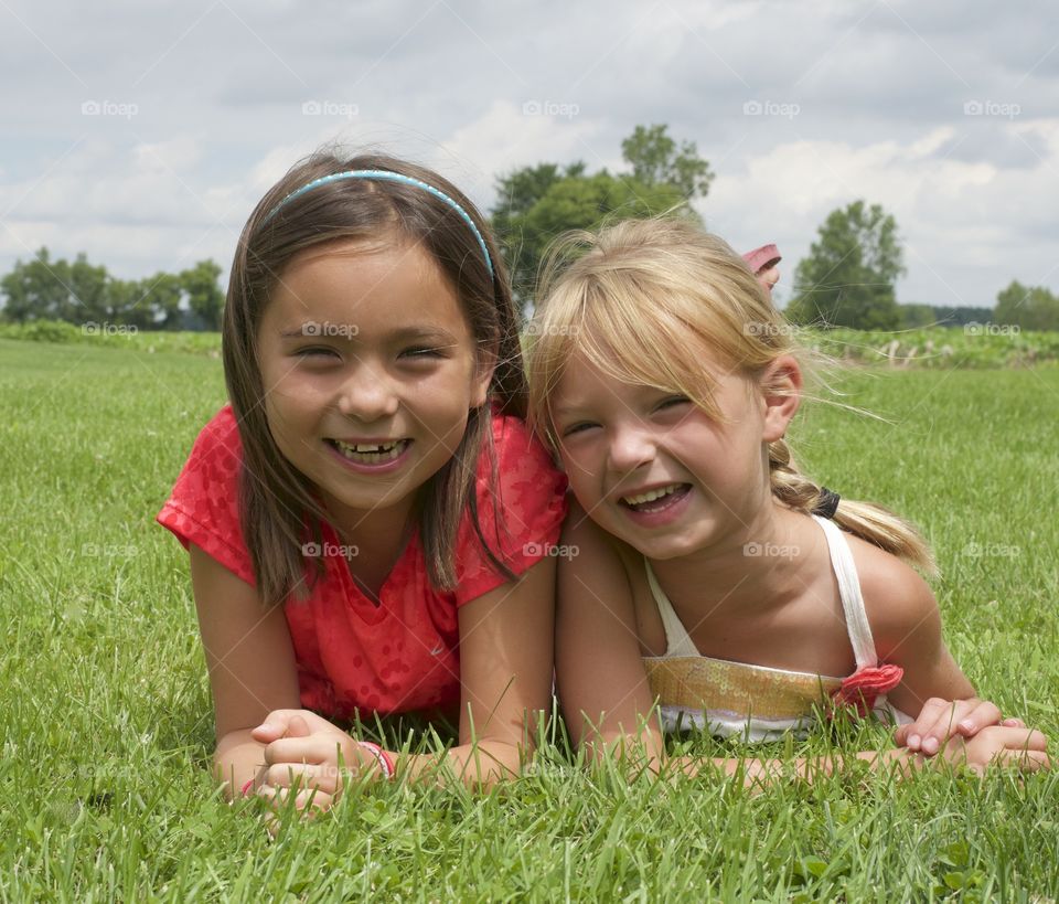 Two sisters lying on grassy field