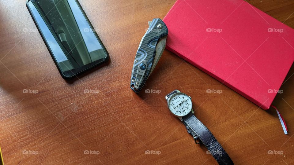 Pobeda men's watch, red notebook, folding knife and smartphone on the table