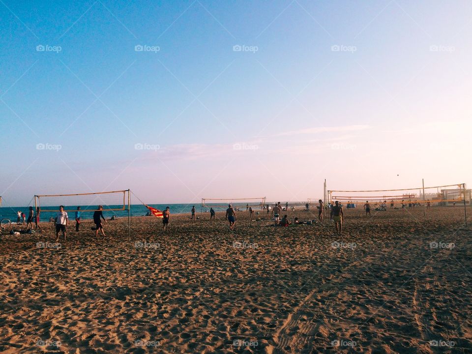 Groups of volleyball nets with people playing at sunset on El Poblenou beach in Barcelona Spain 
