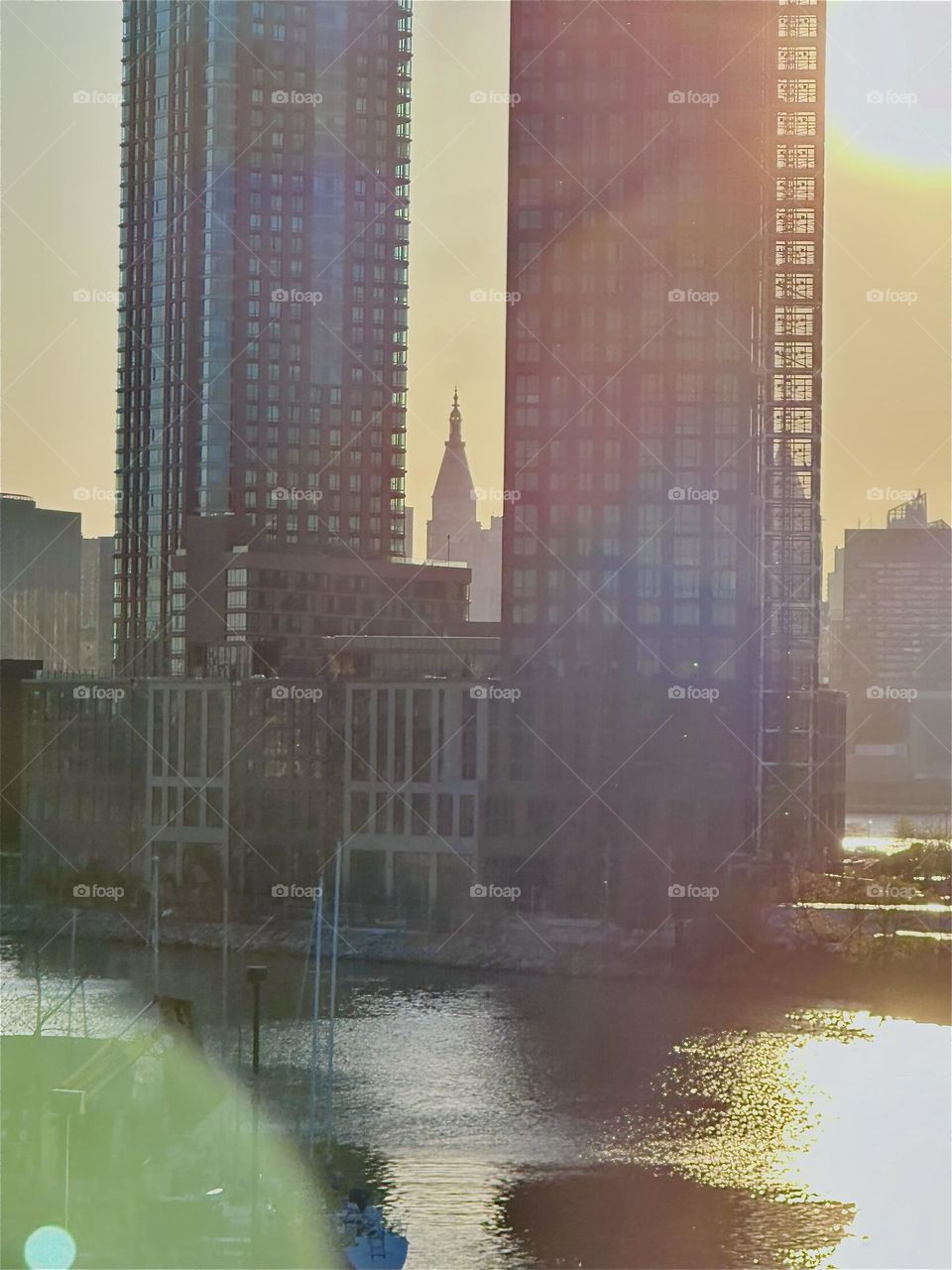 This is a closeup of the view from the „Pulaski Bridge“ at „Newtown Creek“ that connects „Greenpoint“, Bklyn to LIC in the golden hour of sunset. The sun reflects off the „E River“ that shimmers in metallic silver and gold. 2024. Hypnotic Productions