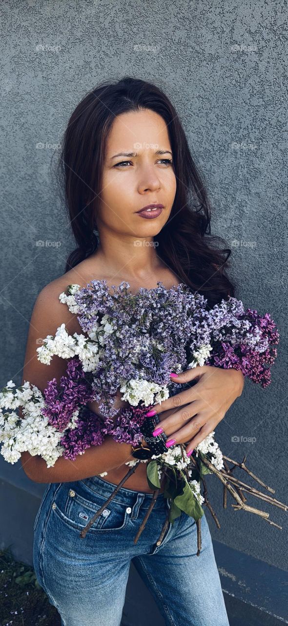 Portrait of young mother with lilac bouquet