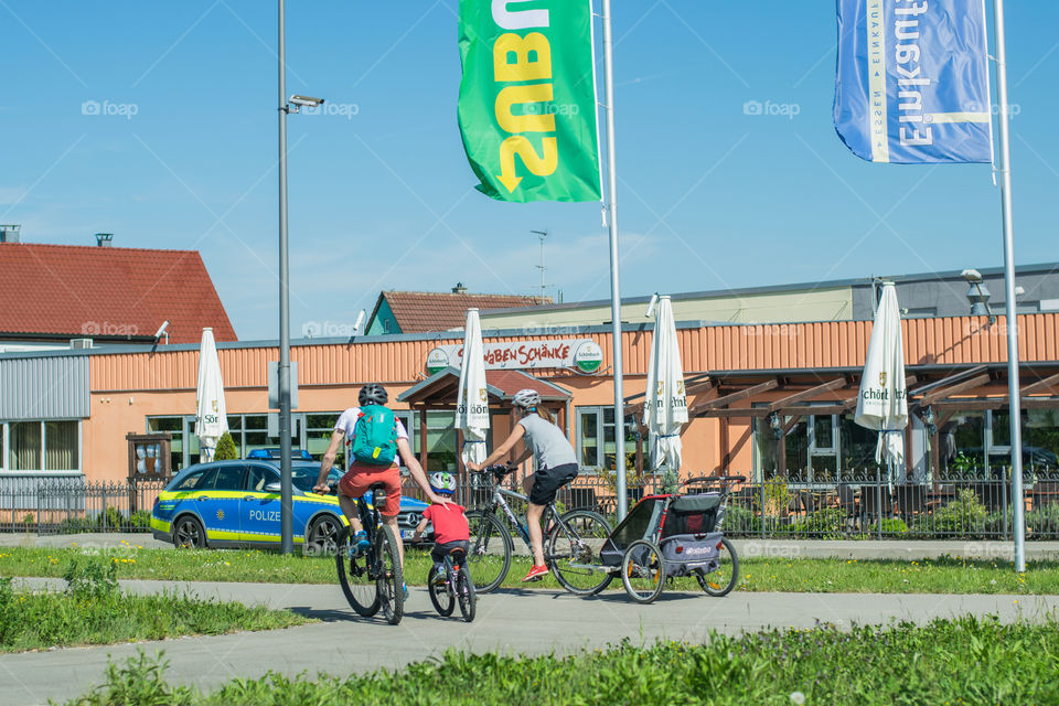 warm, May day, family on a bicycle ride through a small German city. Police car in the background.