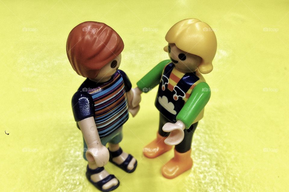 A couple of lego toys holding hands.