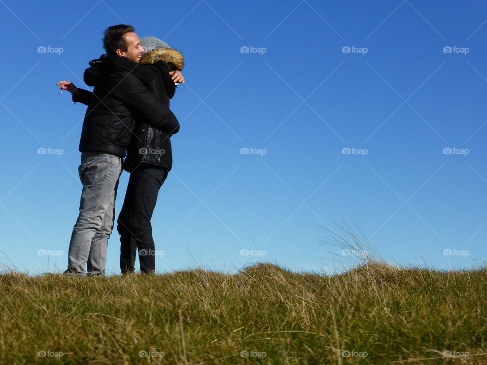 Happy couple embracing against sky