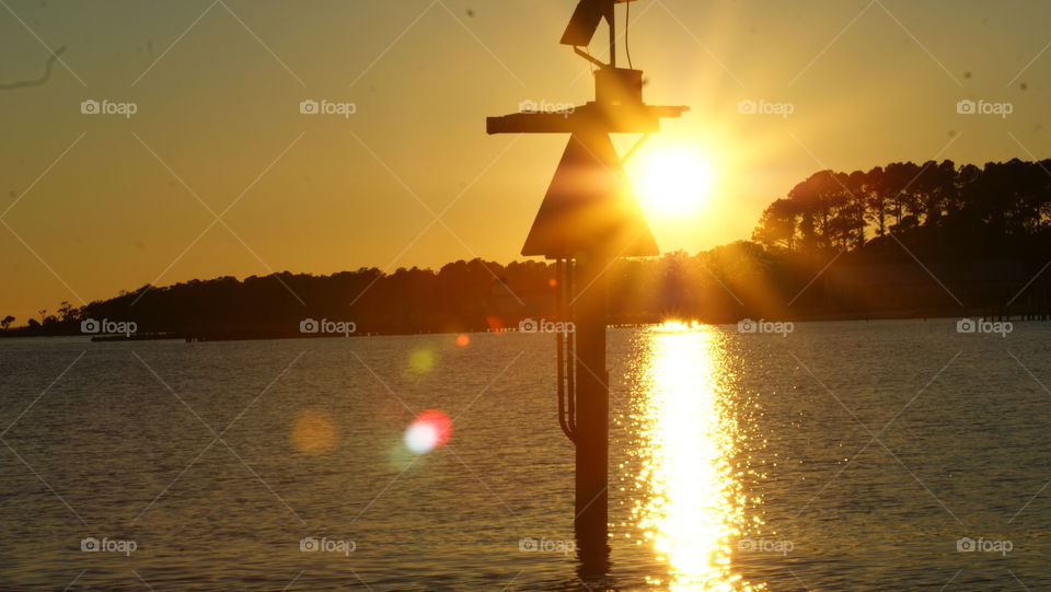 Sunset over the water with a boat marker
